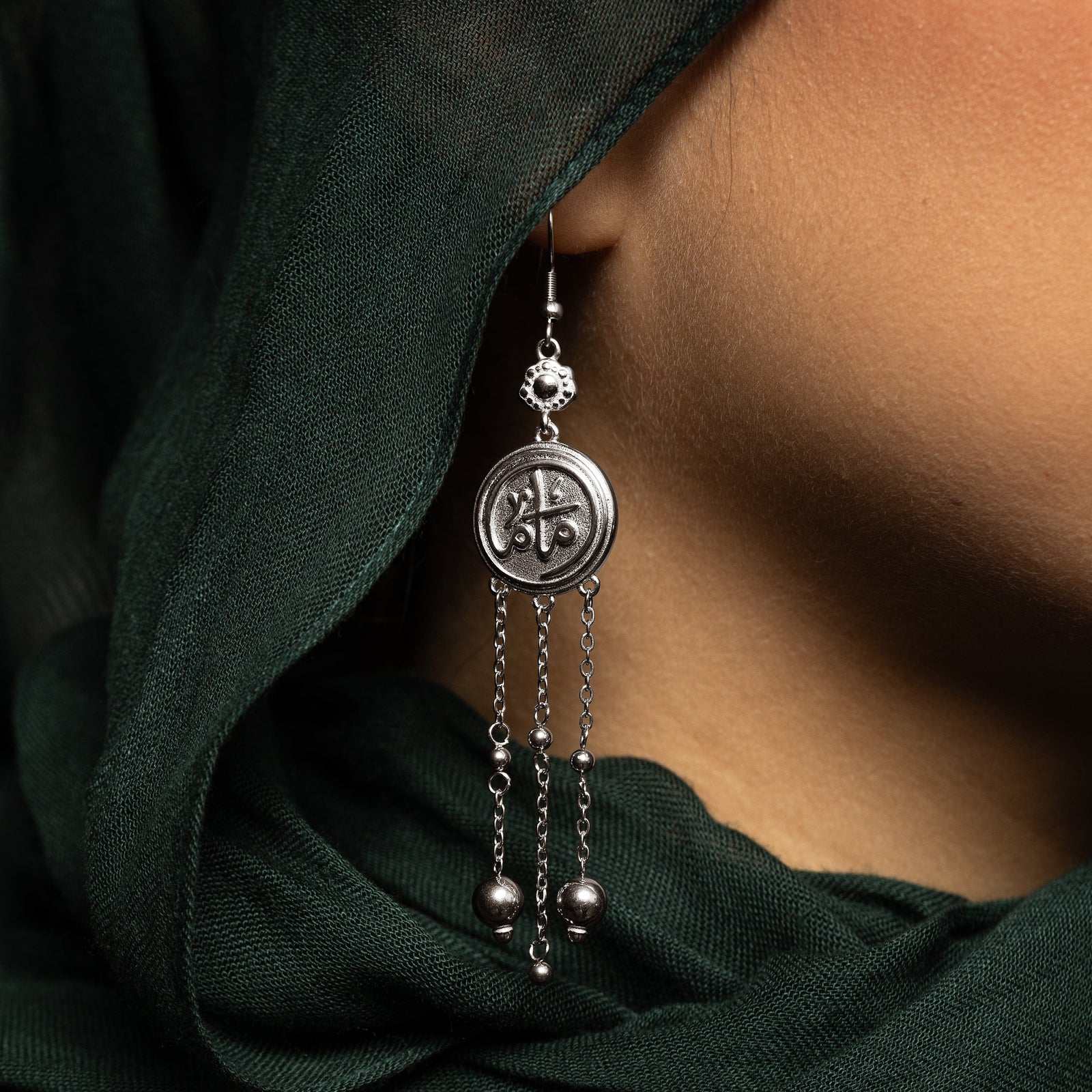 Close up of the gold coin Mama Earrings worn by a model.