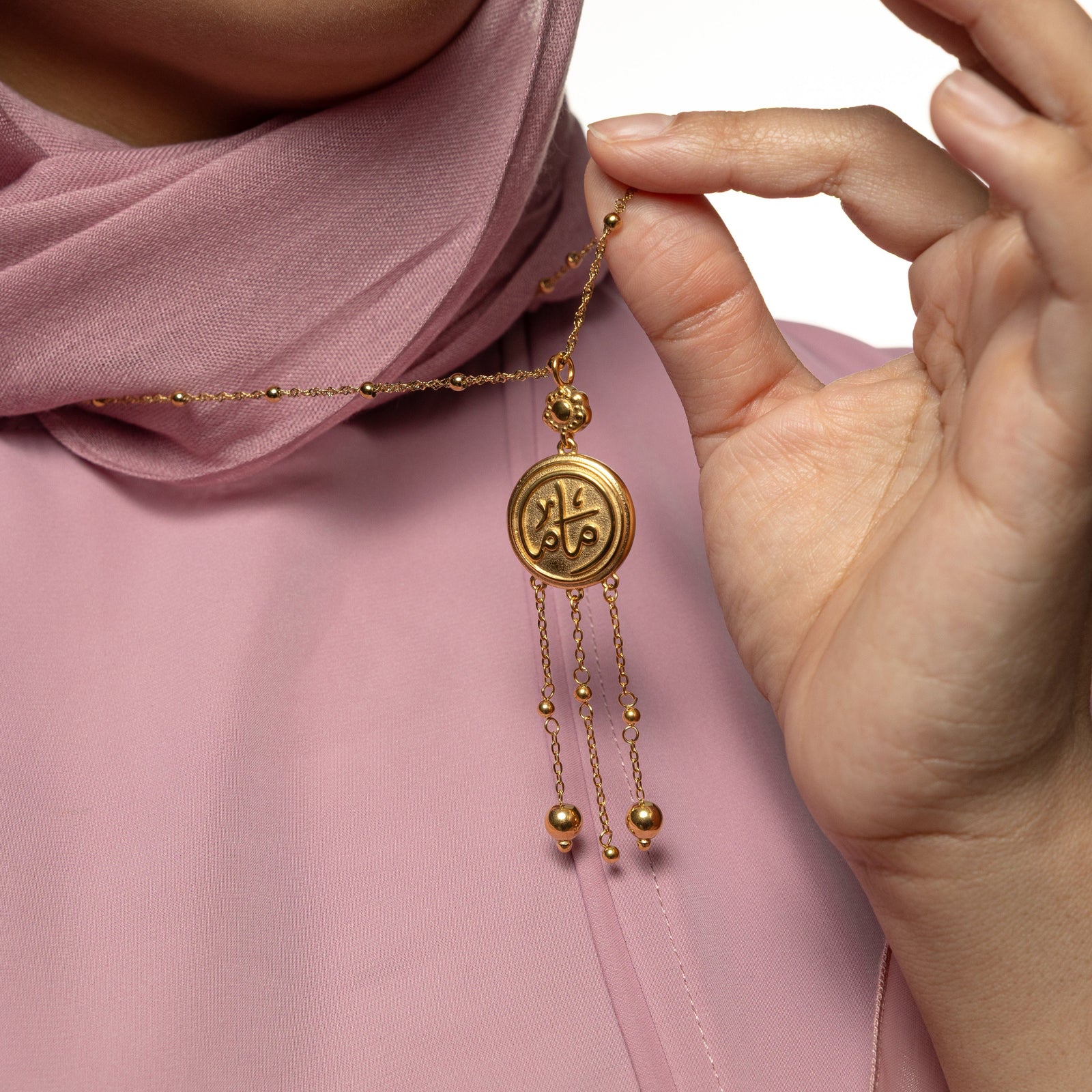 Model holds the chain of the gold Coin Mama Necklace to show the pendant