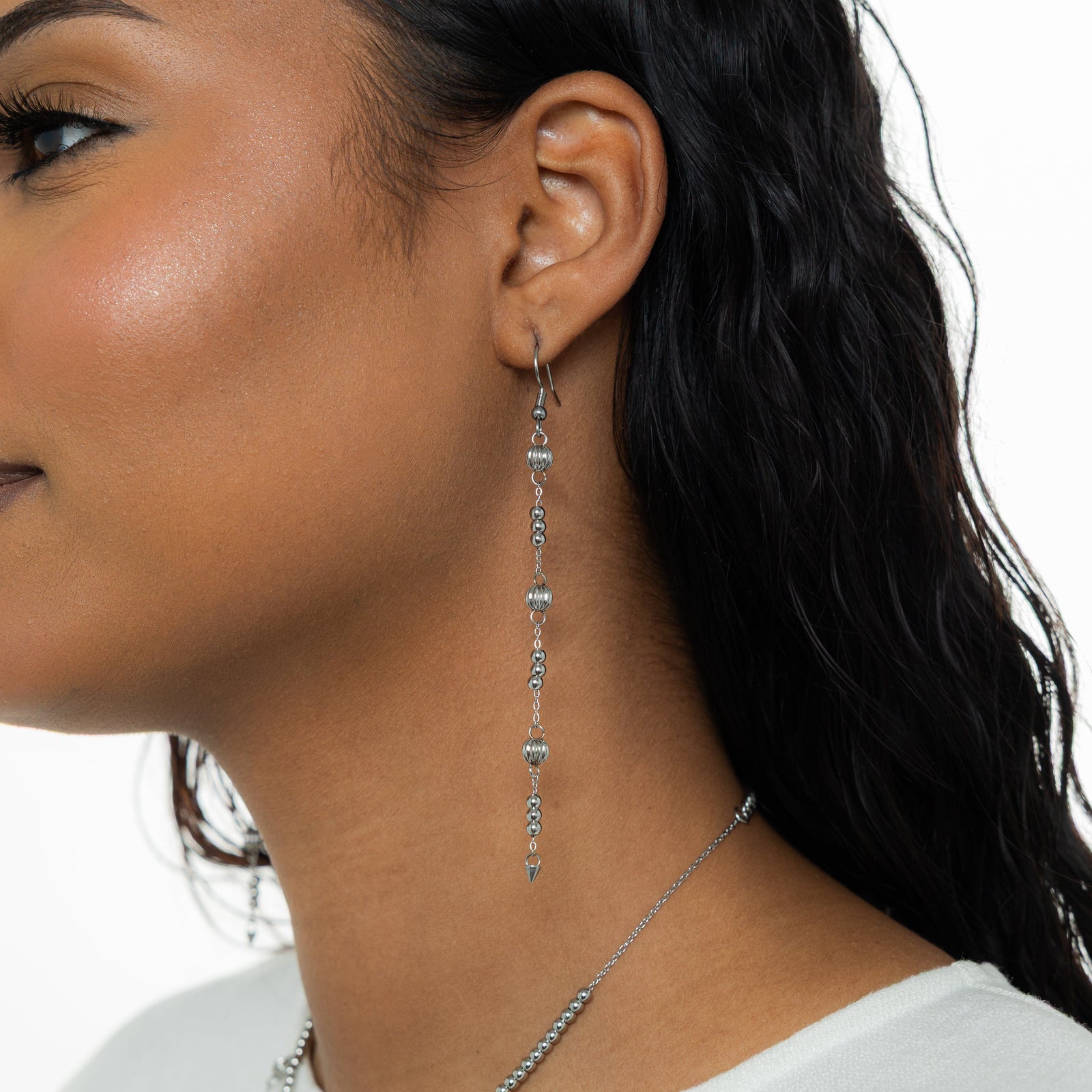 Photo of the left side profile of the model. The model is wearing the silver Comet Earring on their left ear.