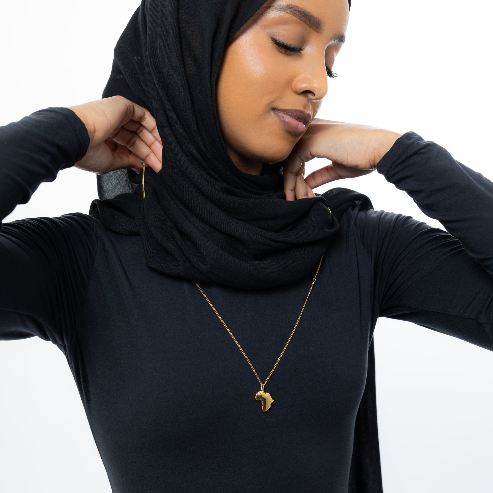 A model wearing a gold-plated country map charm necklace resting delicately on the collarbone, showcasing the charm’s detailed geographic outline.