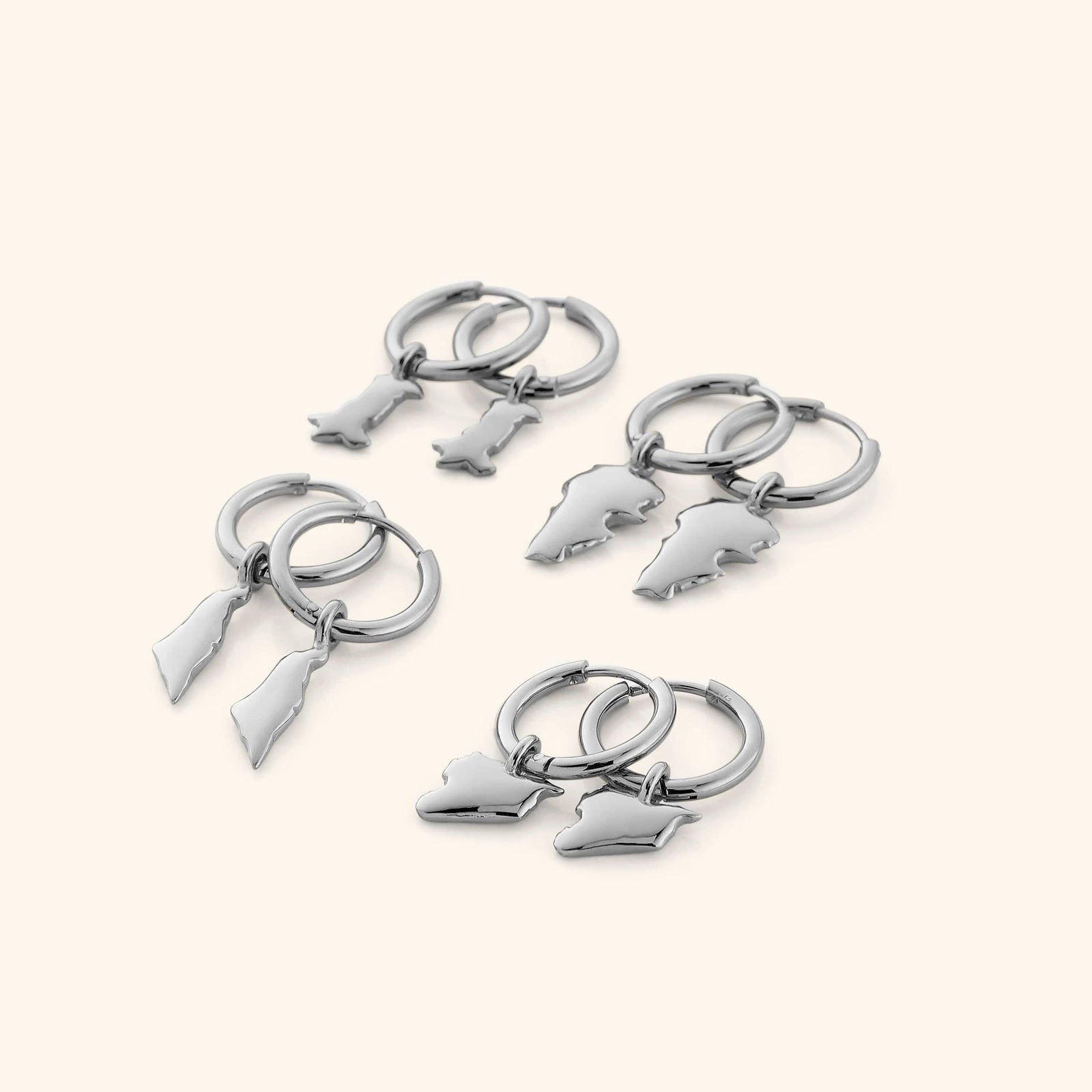 4 different pairs of silver hoop earrings that features outlines of different countries.