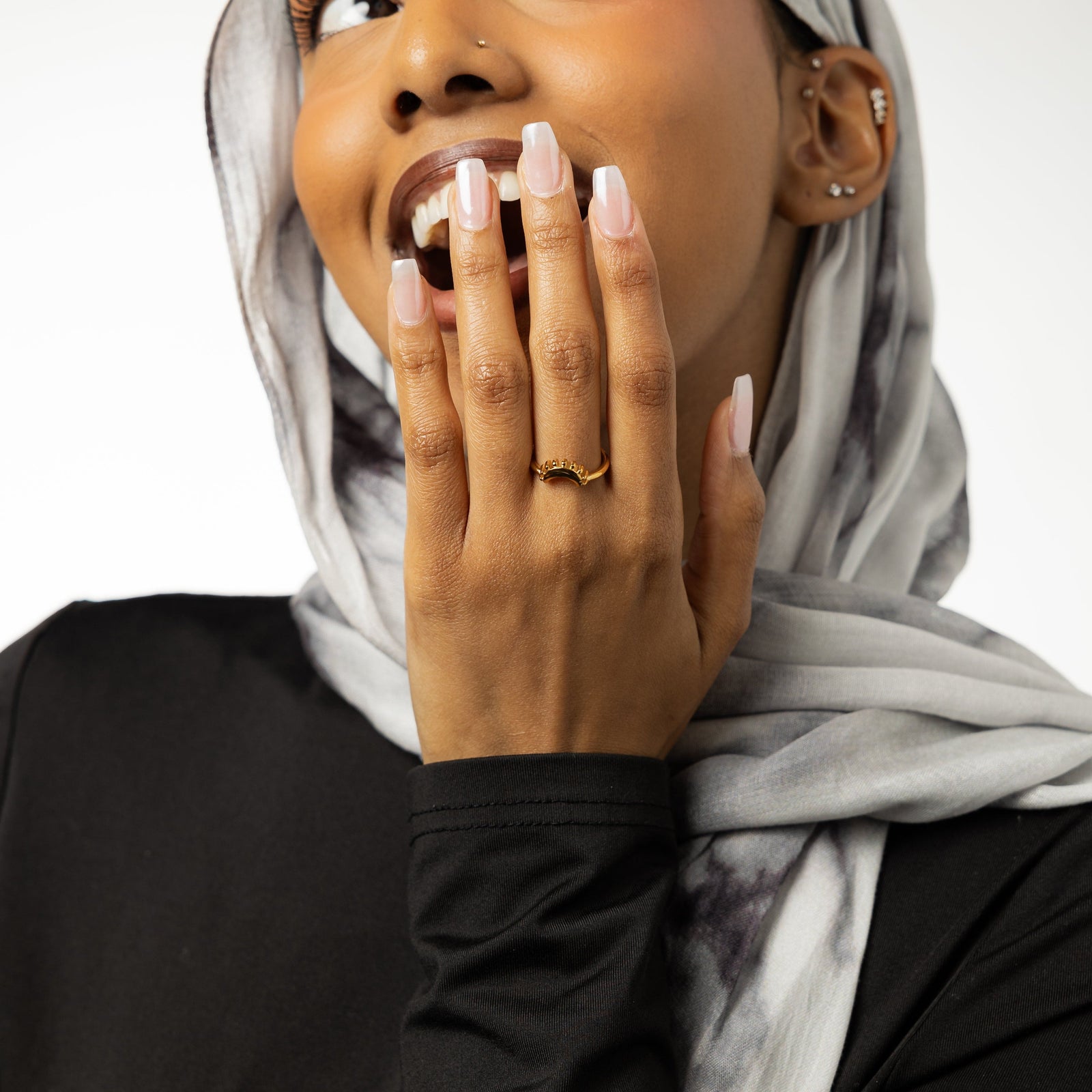 Woman with her hand near her face, wearing a gold crescent ring
