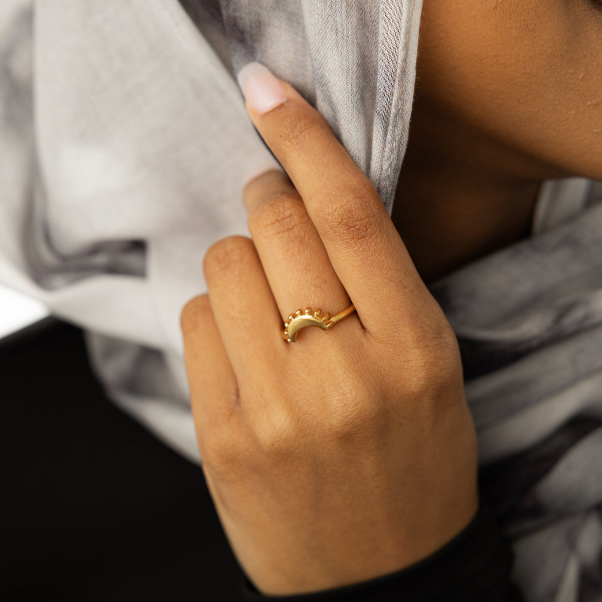 Close-up of a hand wearing a gold crescent ring.