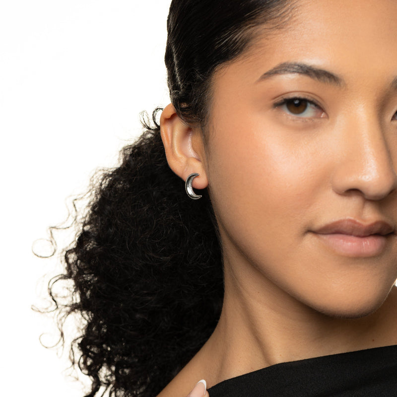 Close-up of a woman wearing a silver dotted crescent earring.