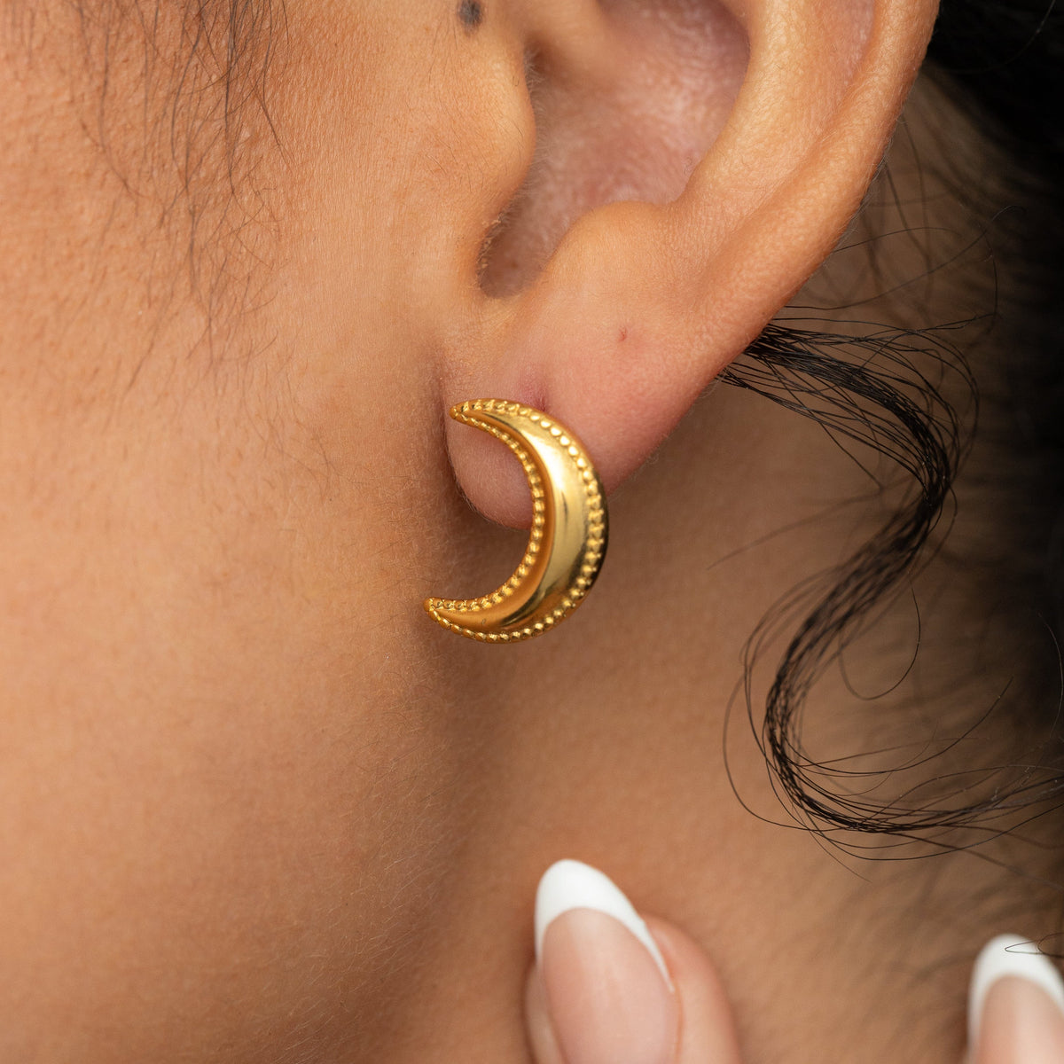 Close-up of a person's ear wearing a Gold dotted crescent earring 