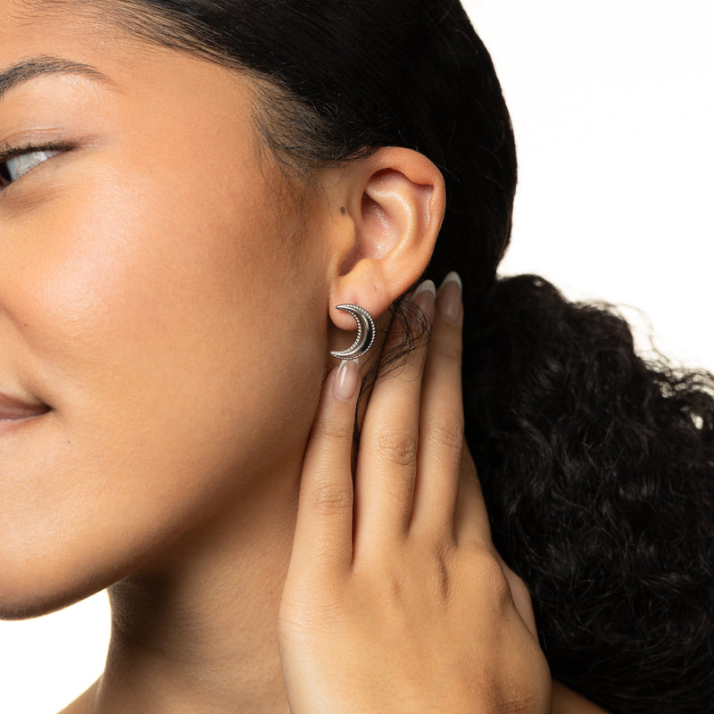 Close-up of a woman wearing a silver dotted crescent earring.