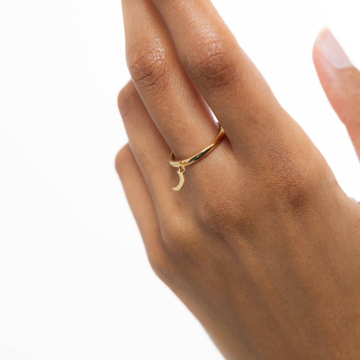 Hand wearing the gold crescent ring, styled on the middle finger with the charm hanging