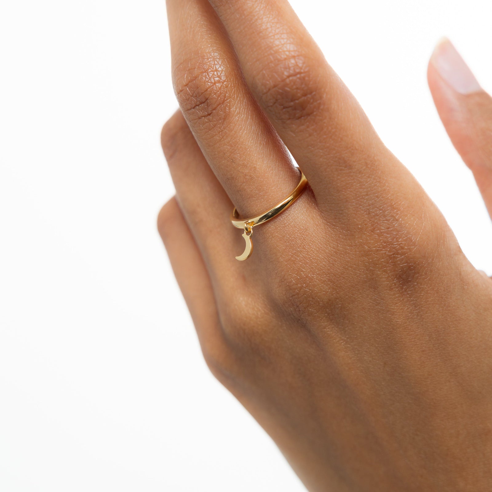 Hand wearing the gold crescent ring, styled on the middle finger with the charm hanging