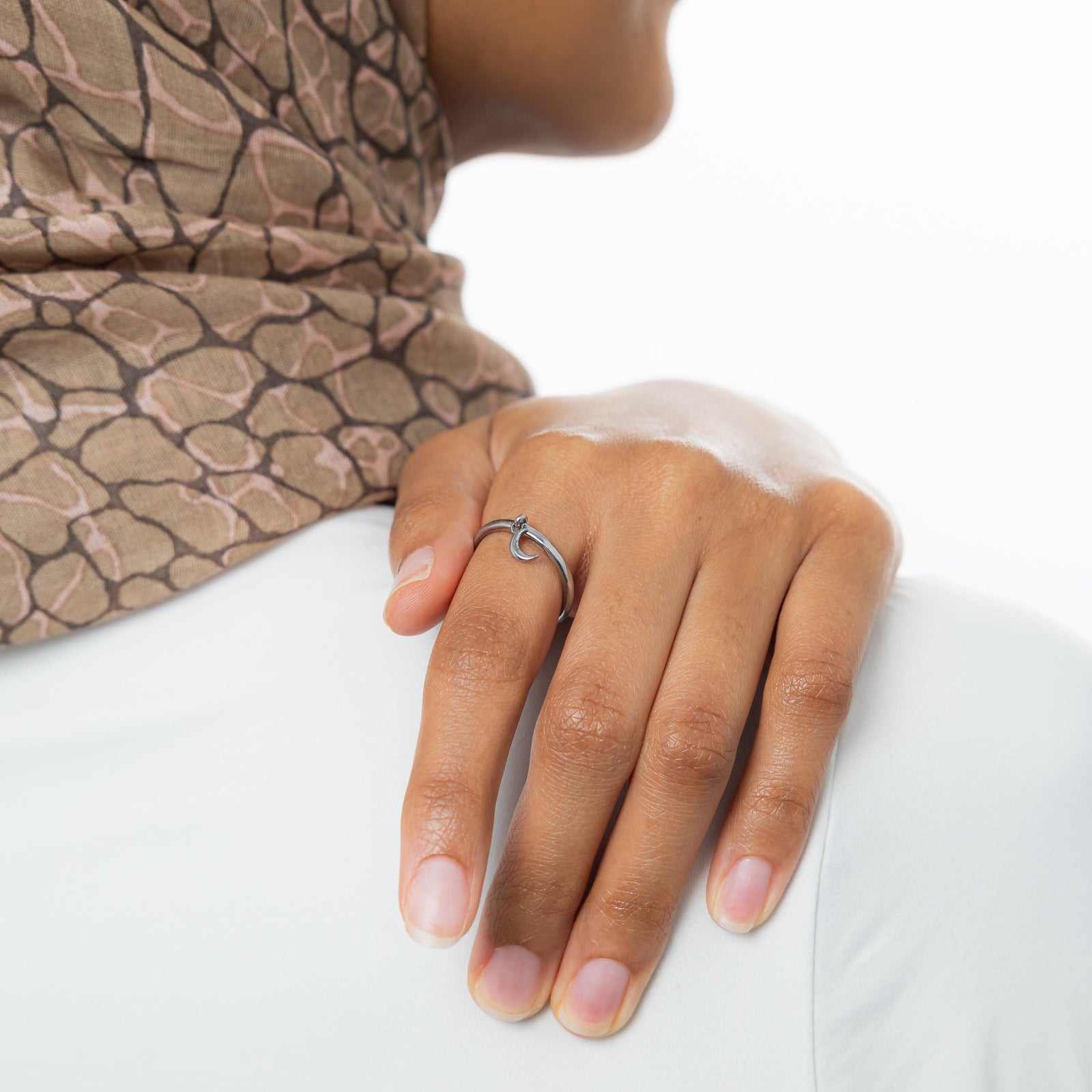 Hand shot with the silver crescent ring worn on the index finger