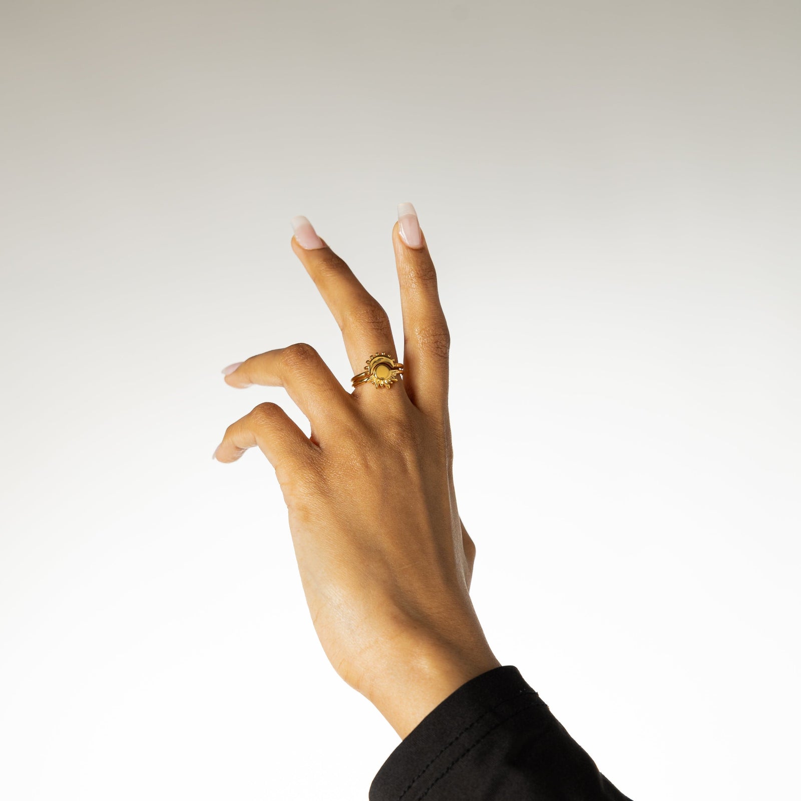 Hand lifted wearing both the gold sun ring and gold moon ring stacked together