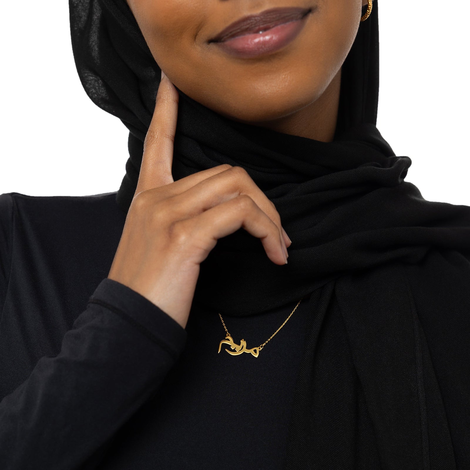 A model wearing the Custom Name Necklace in 14K solid gold at a 16-inch length. The necklace rests gracefully on the collarbone, showcasing the personalized Arabic name pendant against a simple, neutral-toned outfit.