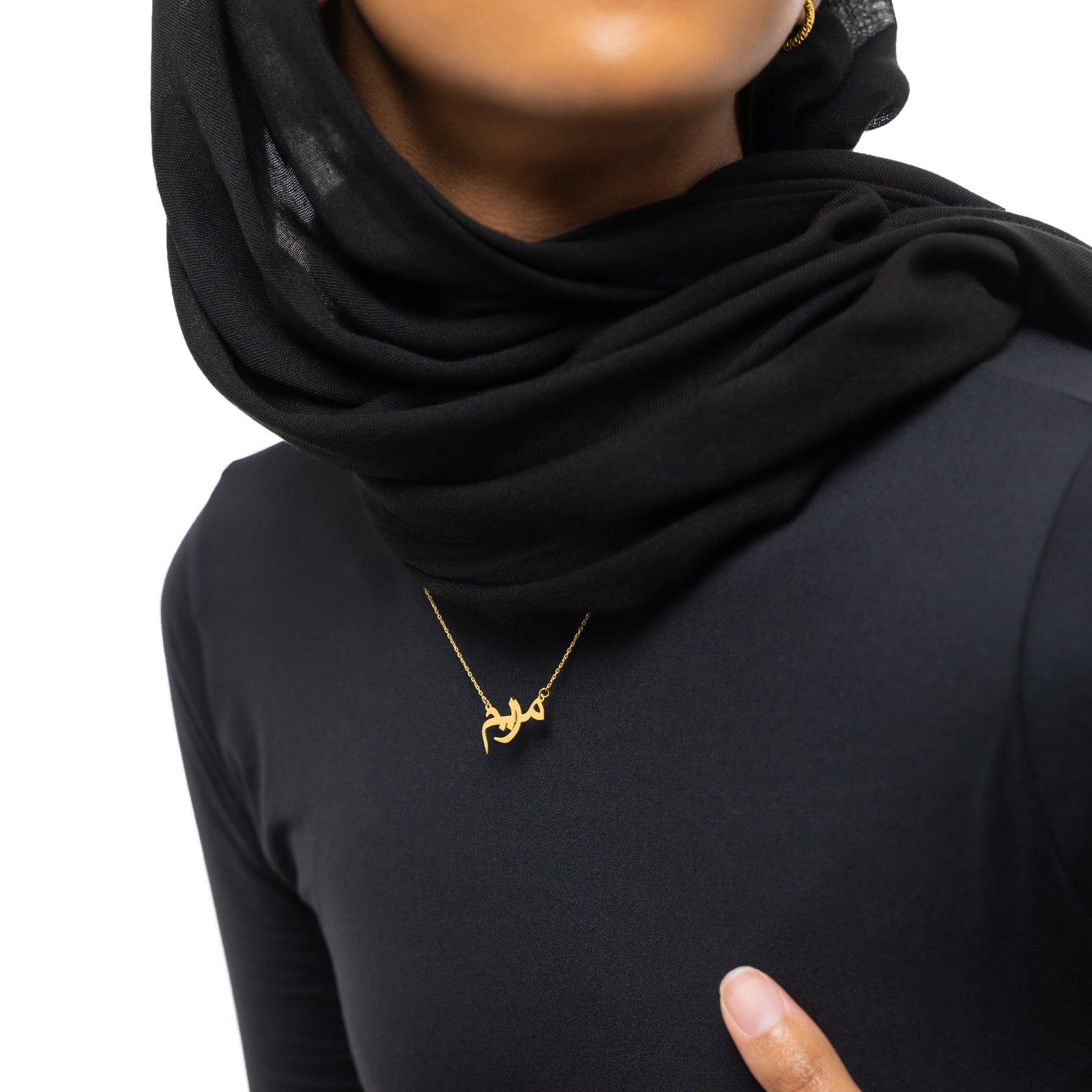 A model wearing the Custom Name Necklace in 14K solid gold at a 16-inch length. The necklace rests gracefully on the collarbone, showcasing the personalized Arabic name pendant against a simple, neutral-toned outfit.