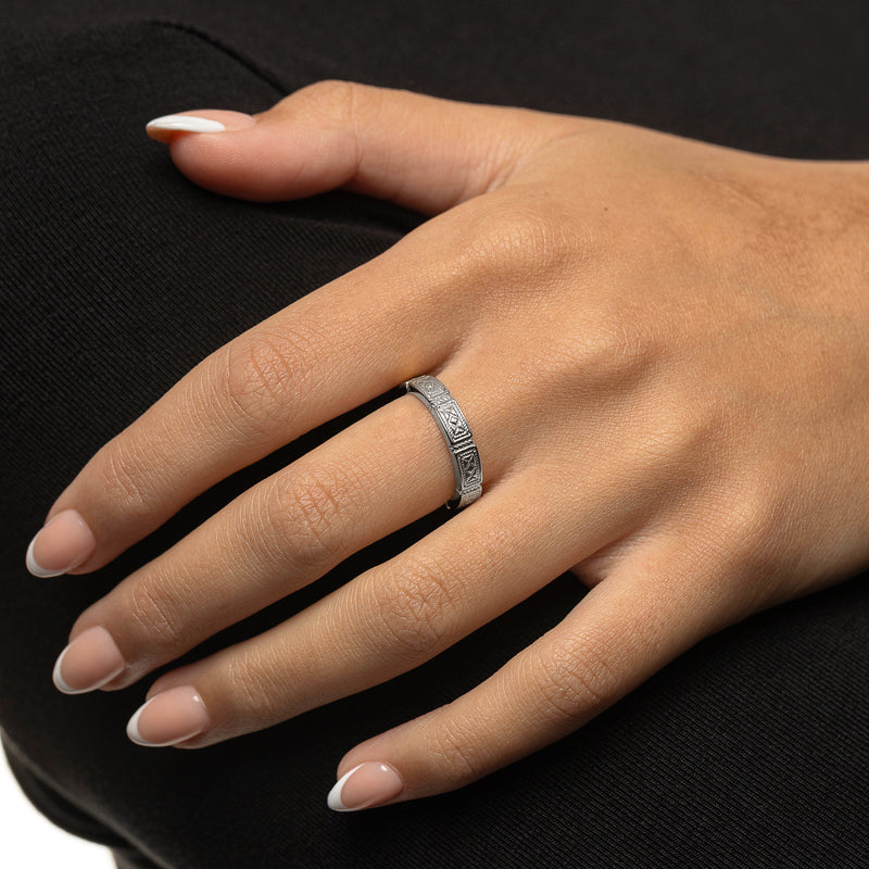 Woman wearing a silver Damascus Tile Ring with engraved tile-style patterns on her finger pimage_ shown in a close-up hand shot.