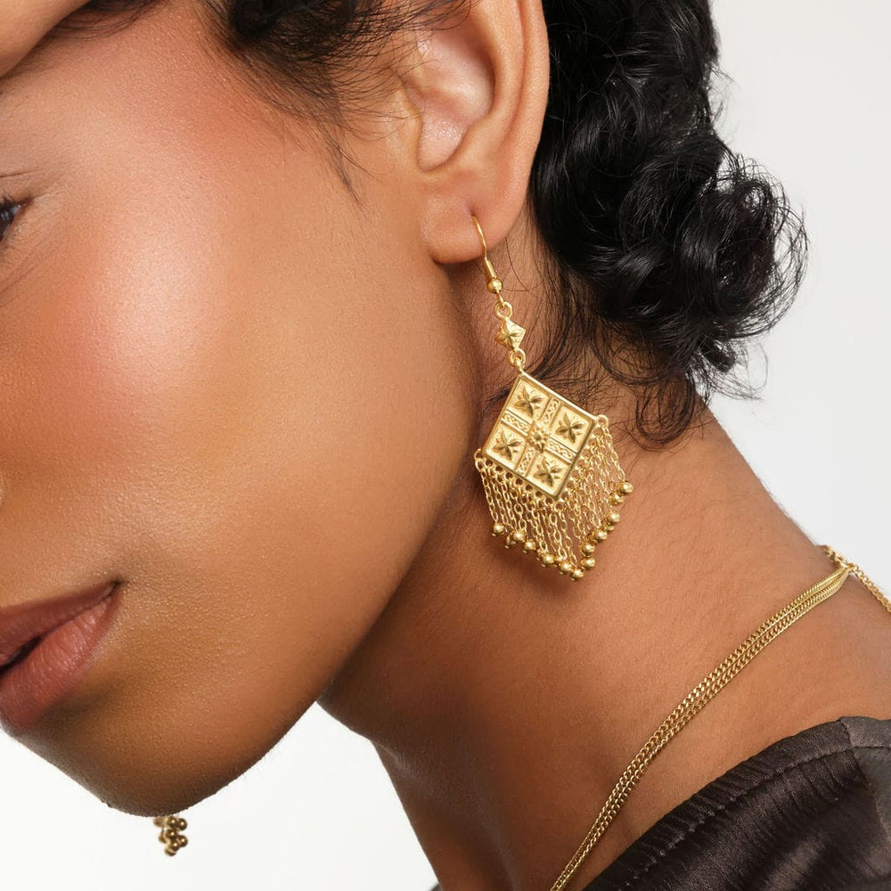 Close up of the gold Dancing Kite Earrings on the model's left ear.