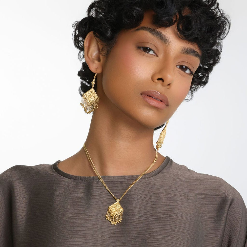 Photo of the model looking at the camera. The model is wearing the gold Dancing Kite Earrings.