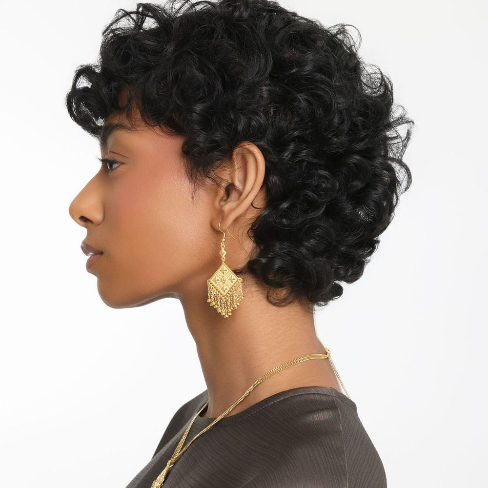 Photo of the left side profile of the model. The model is wearing the gold Dancing Kite Earrings.