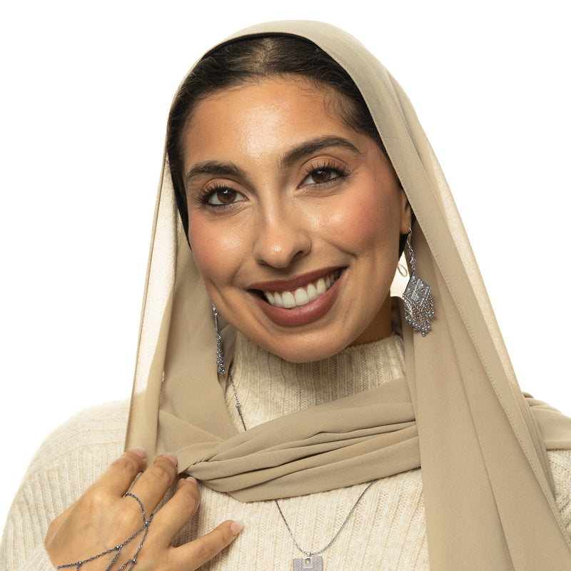 Woman wearing gold Dancing Kite Earrings pimage_ styled with a beige scarf and cream sweater.