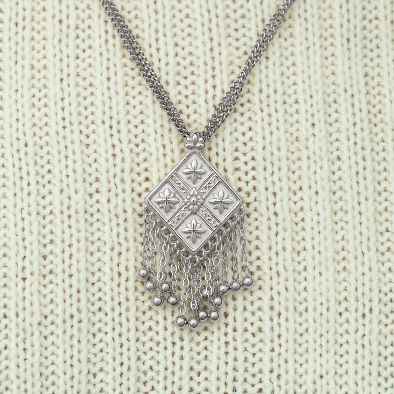 Close-up of a silver dancing kite necklace pimage_ styled against a cream ribbed sweater.