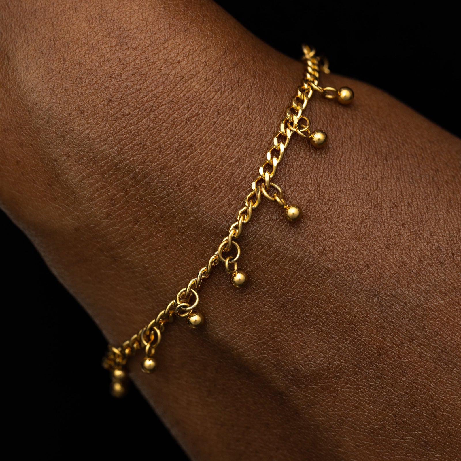 Close up of the gold Dangling Dotted Bracelet worn by a model.