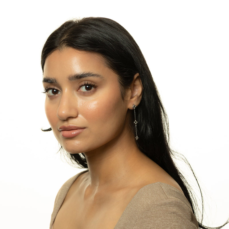Woman wearing the silver Dangling Henna Earrings with hair tucked back pimage_ styled with a neutral top.