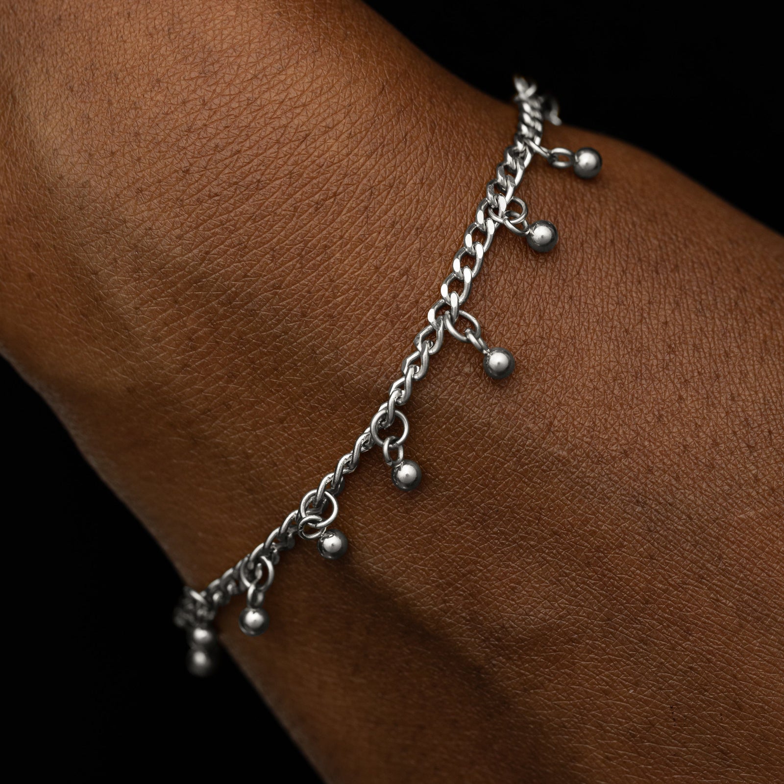 Close up of the silver Dangling Dotted Bracelet worn by a model.