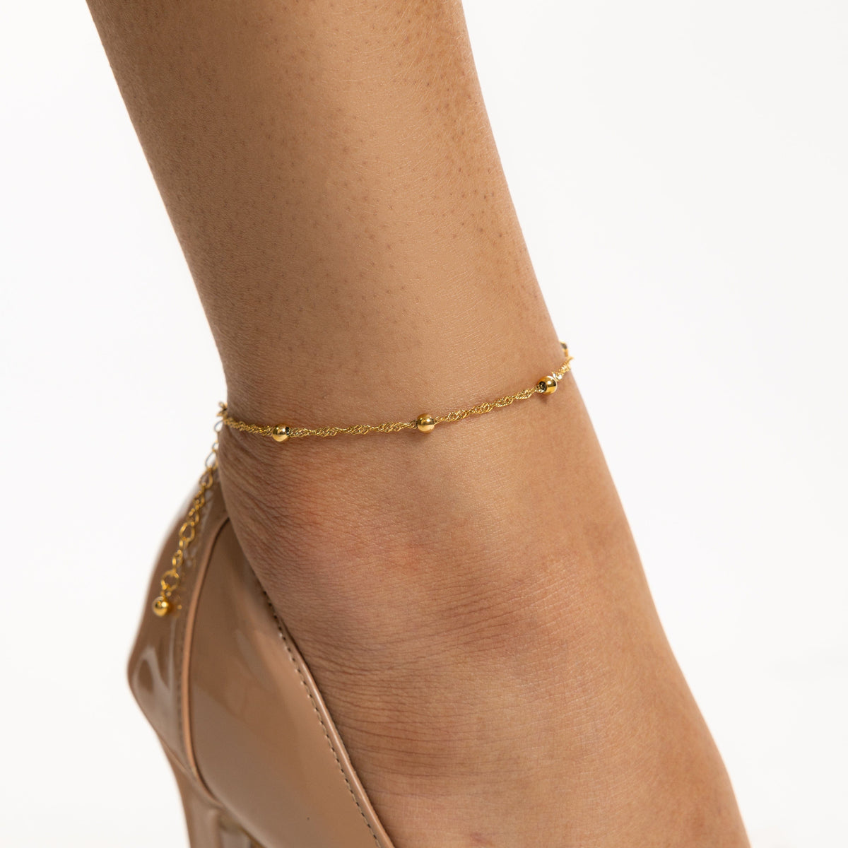 Close up of the gold Dotted Twisted Anklet as worn by the model