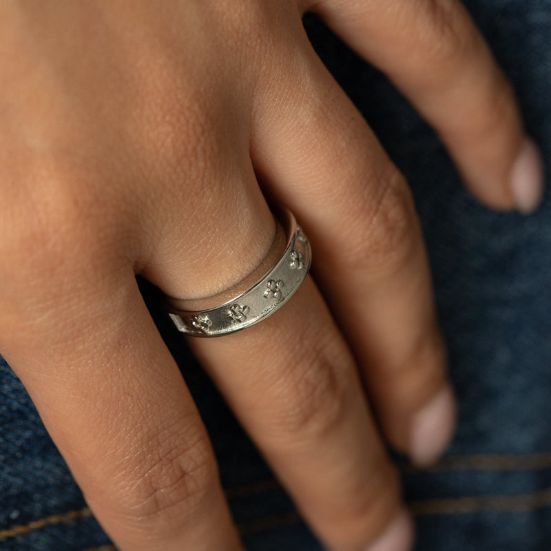 Close-up of a hand wearing the silver Dotted Henna Ring pimage_ showcasing the engraved dotted floral details against denim.