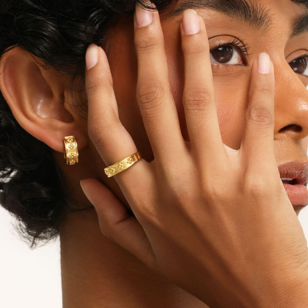 Close up of the model's right hand touching the right side of their face. The model is wearing the gold Dotted Henna Ring on their right index finger.