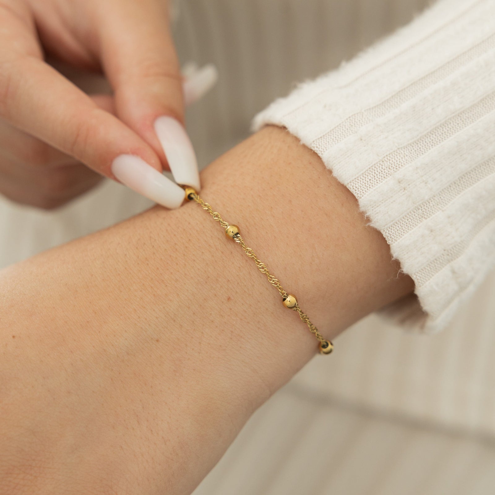 Close up of the gold Dotted Twisted Bracelet as worn by the model on their left wrist.