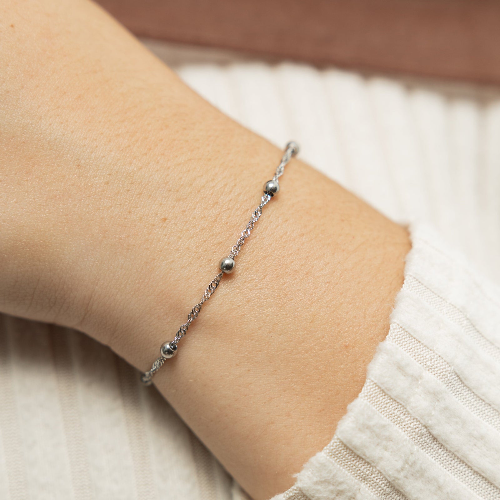 Close up of the silver Dotted Twisted Bracelet as worn by the model on their left wrist.