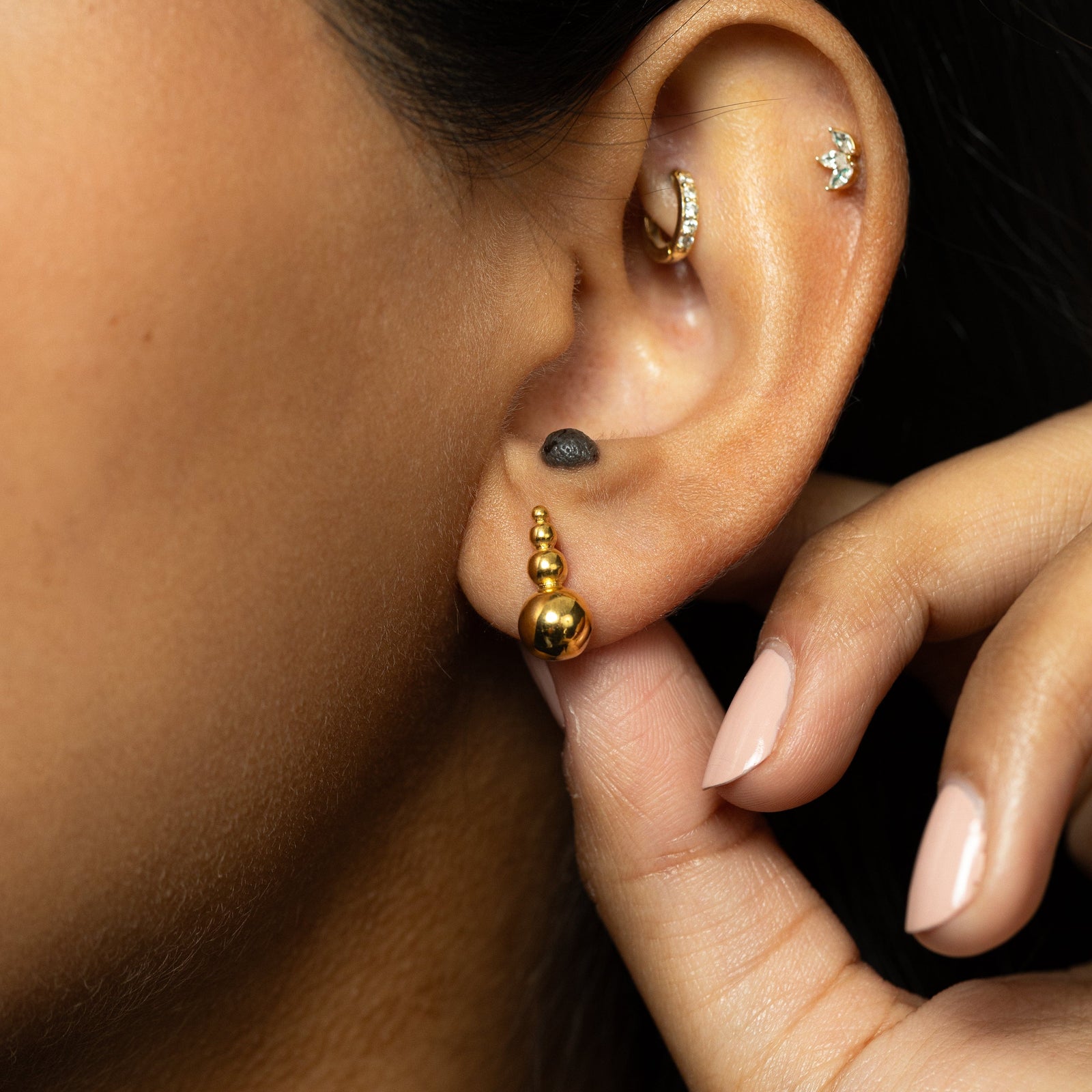 Close-up of the gold Dotted Studs being adjusted by hand.