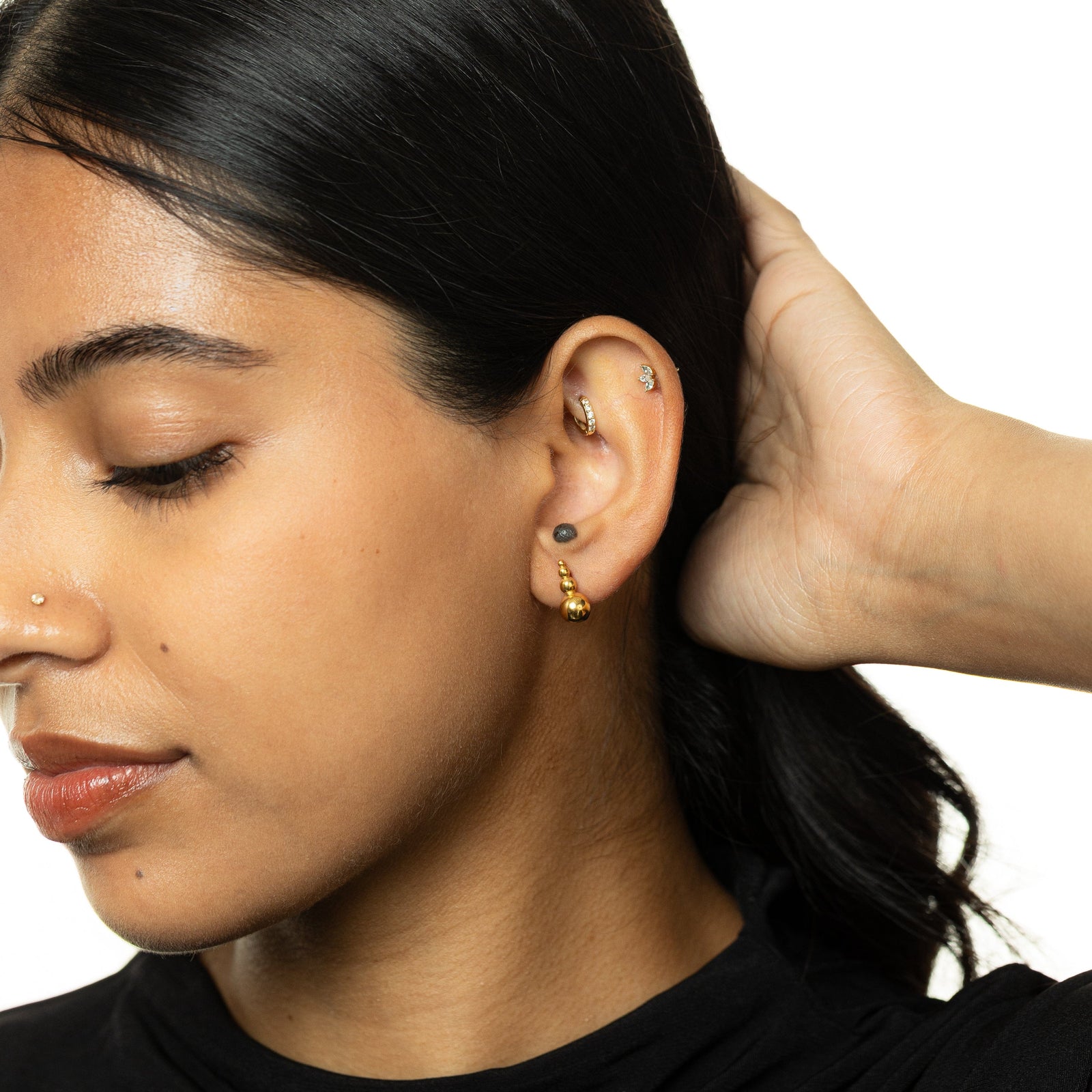 Woman wearing the gold Dotted Studs close to the ear, styled with hair tucked back.