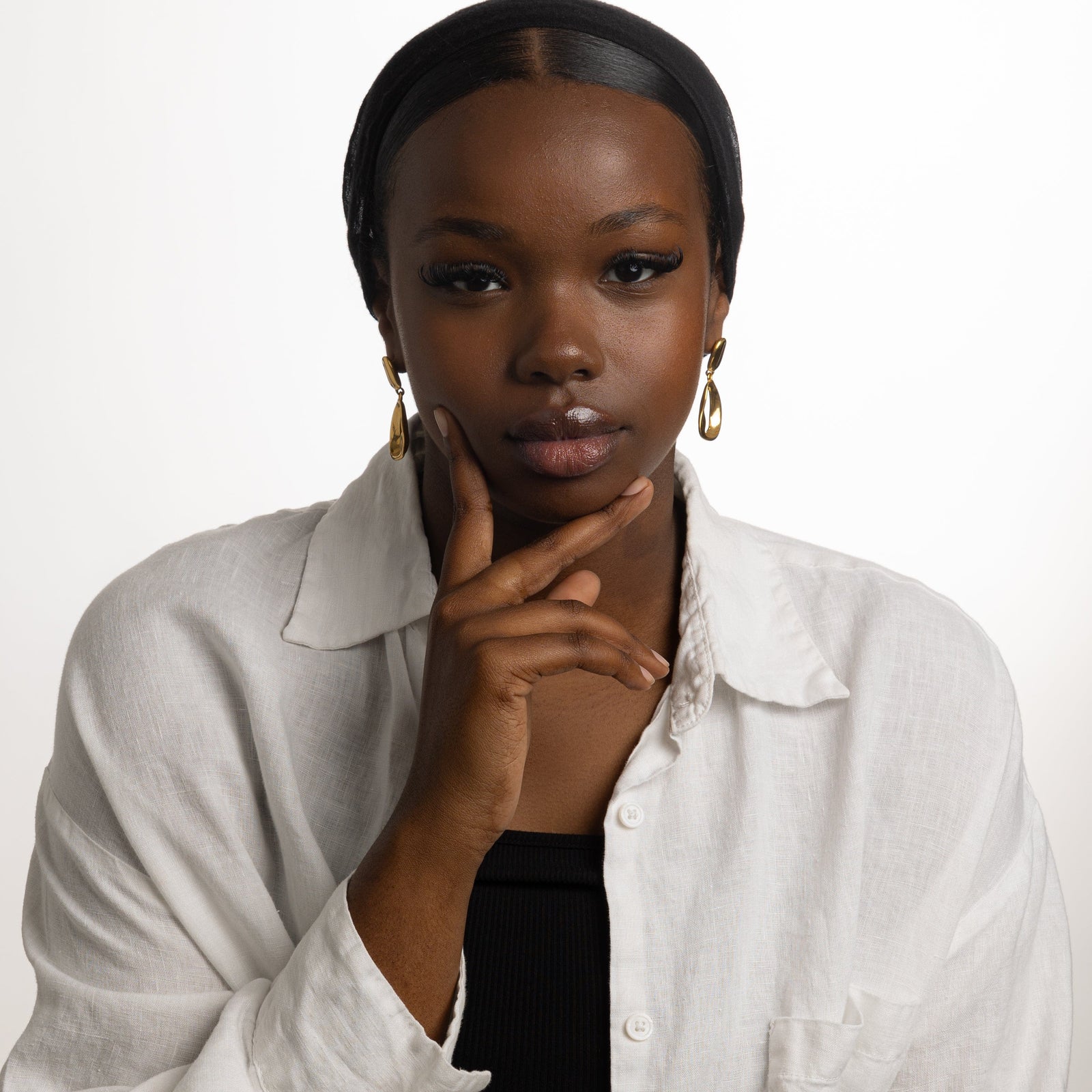 Photo of the model looking at the camera. The model is wearing the gold Droop Earrings.