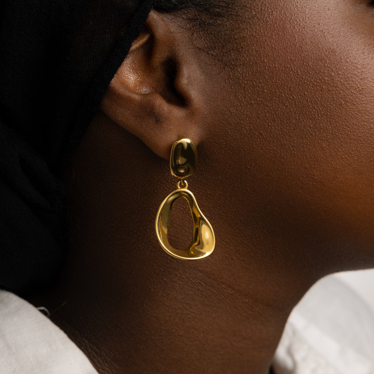 Close up of the gold Droop Earrings as worn by the model on their right ear.