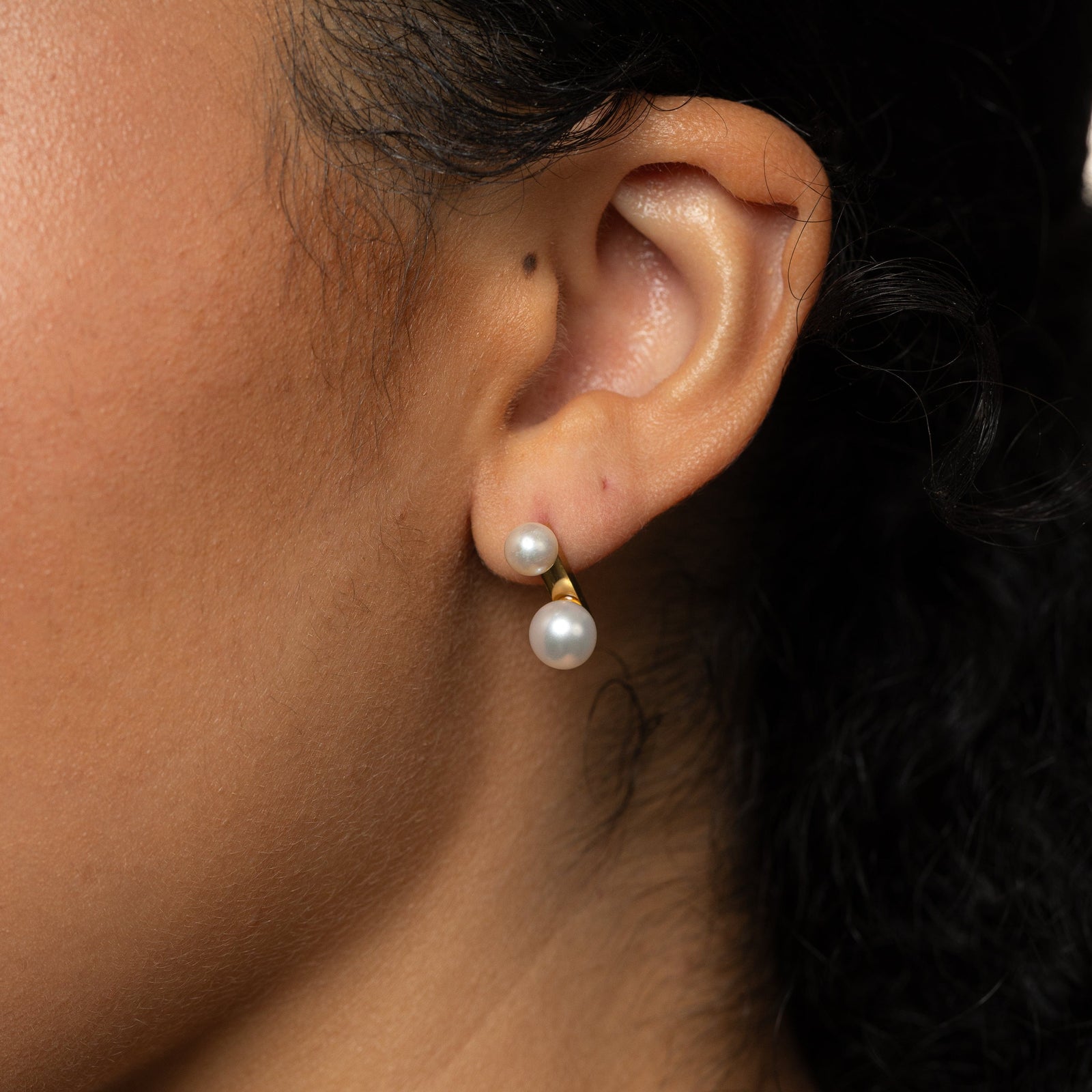 Close-up of an ear wearing gold duo pearl stud