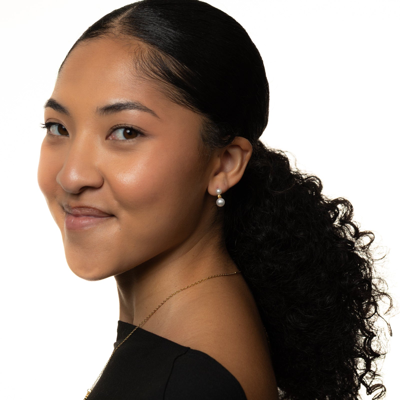 Woman with a ponytail wearing duo pearl stud, shot on a white background