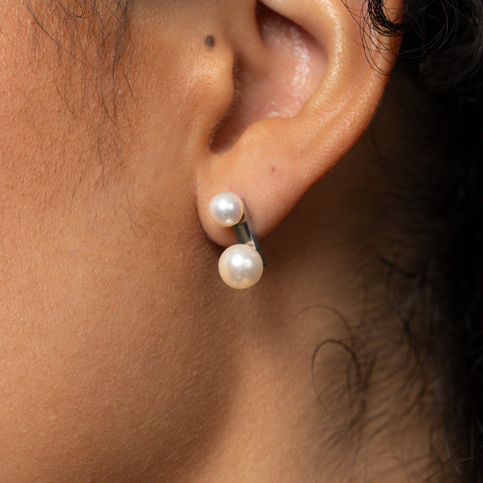 Close-up of an ear wearing a silver duo pearl stud