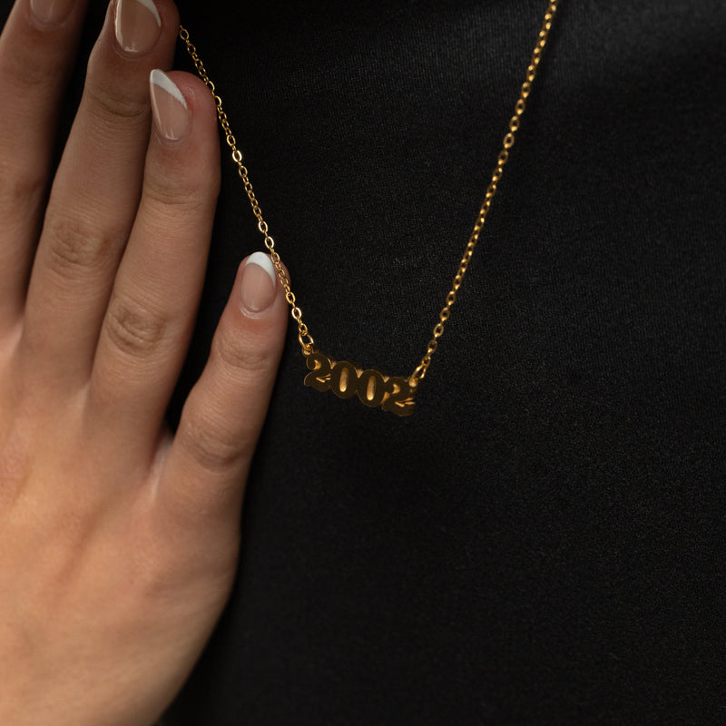 Gold english birth year necklace against a black background