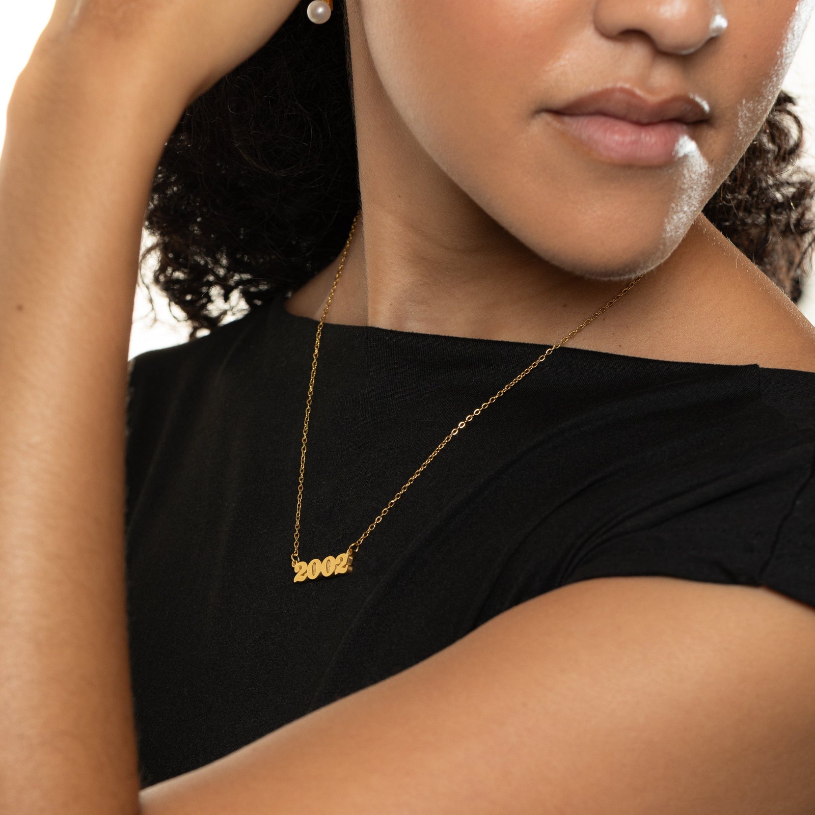 Woman wearing a gold english birth year necklace with '2002' pendant