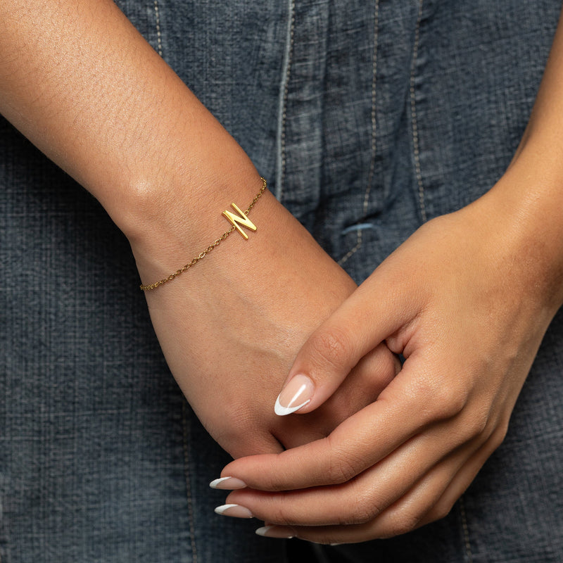Gold english letter bracelet on a wrist with a denim background