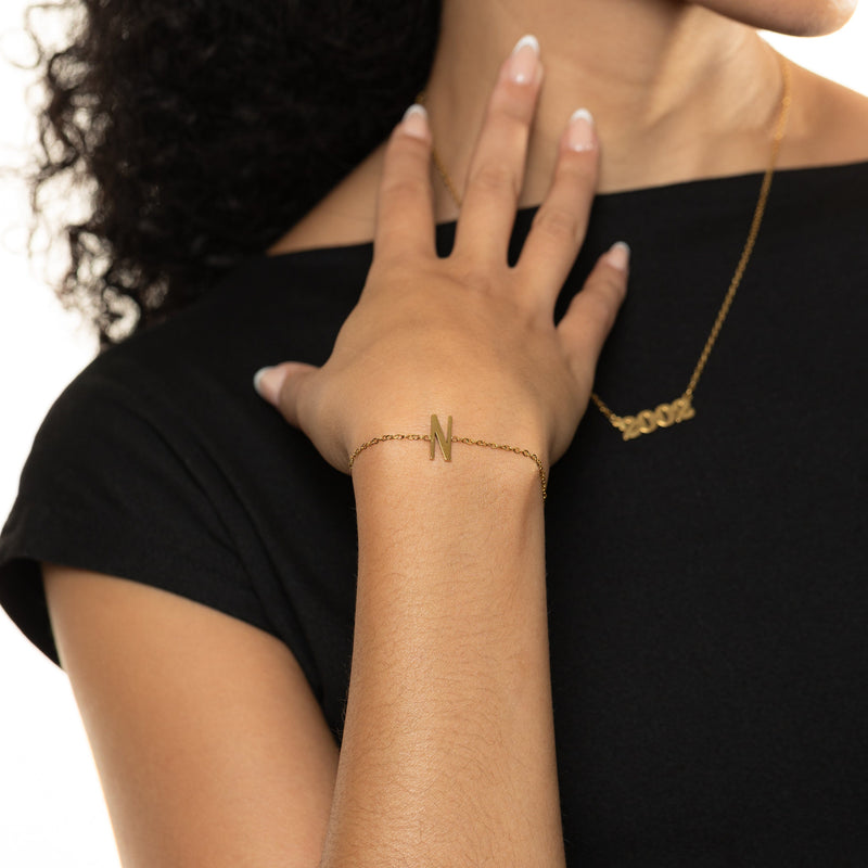 Woman wearing a gold bracelet with an english letter 'N' design
