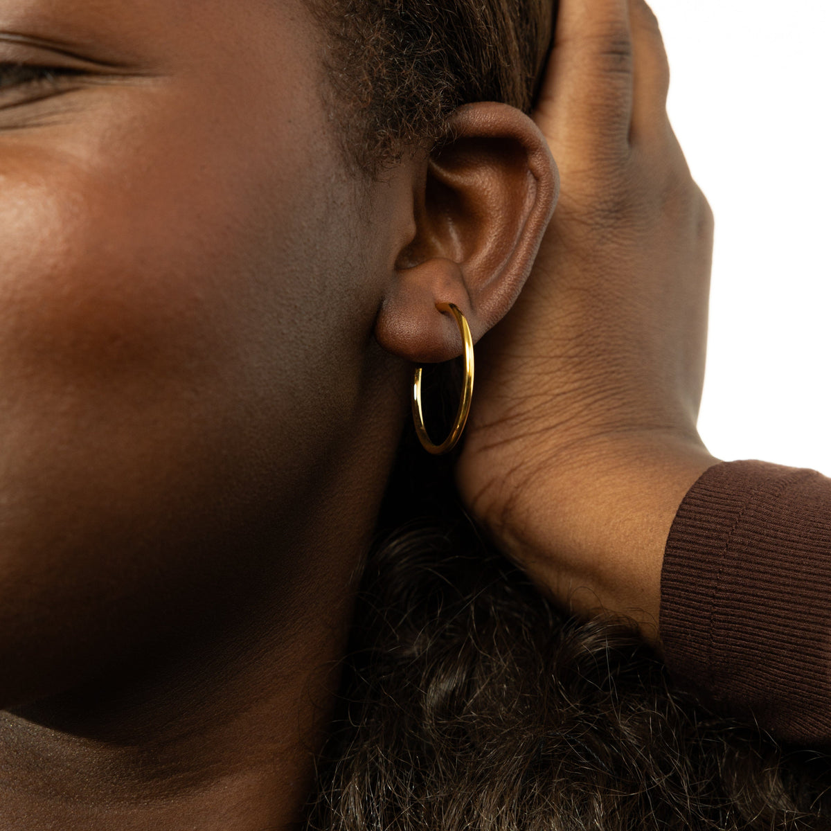 Close up of the gold Essential Open Hoops | 26mm as worn by the model on their left ear.