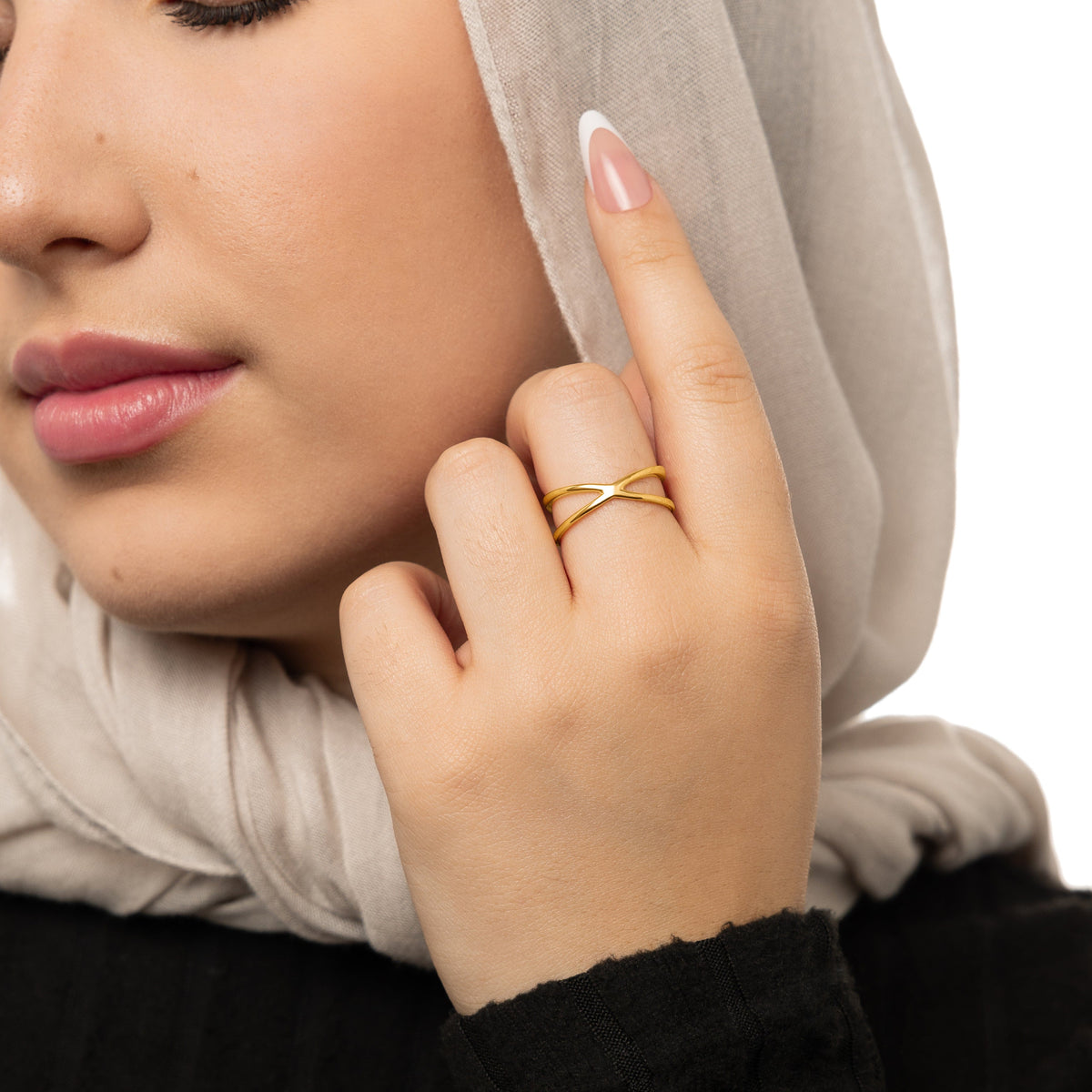 Woman wearing a gold essential intersection ring on her middle finger, styled with a light beige hijab.