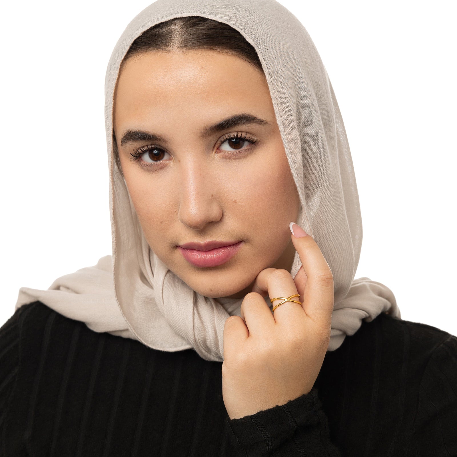 Woman wearing a gold essential intersection ring, styled with a beige hijab and black ribbed top.