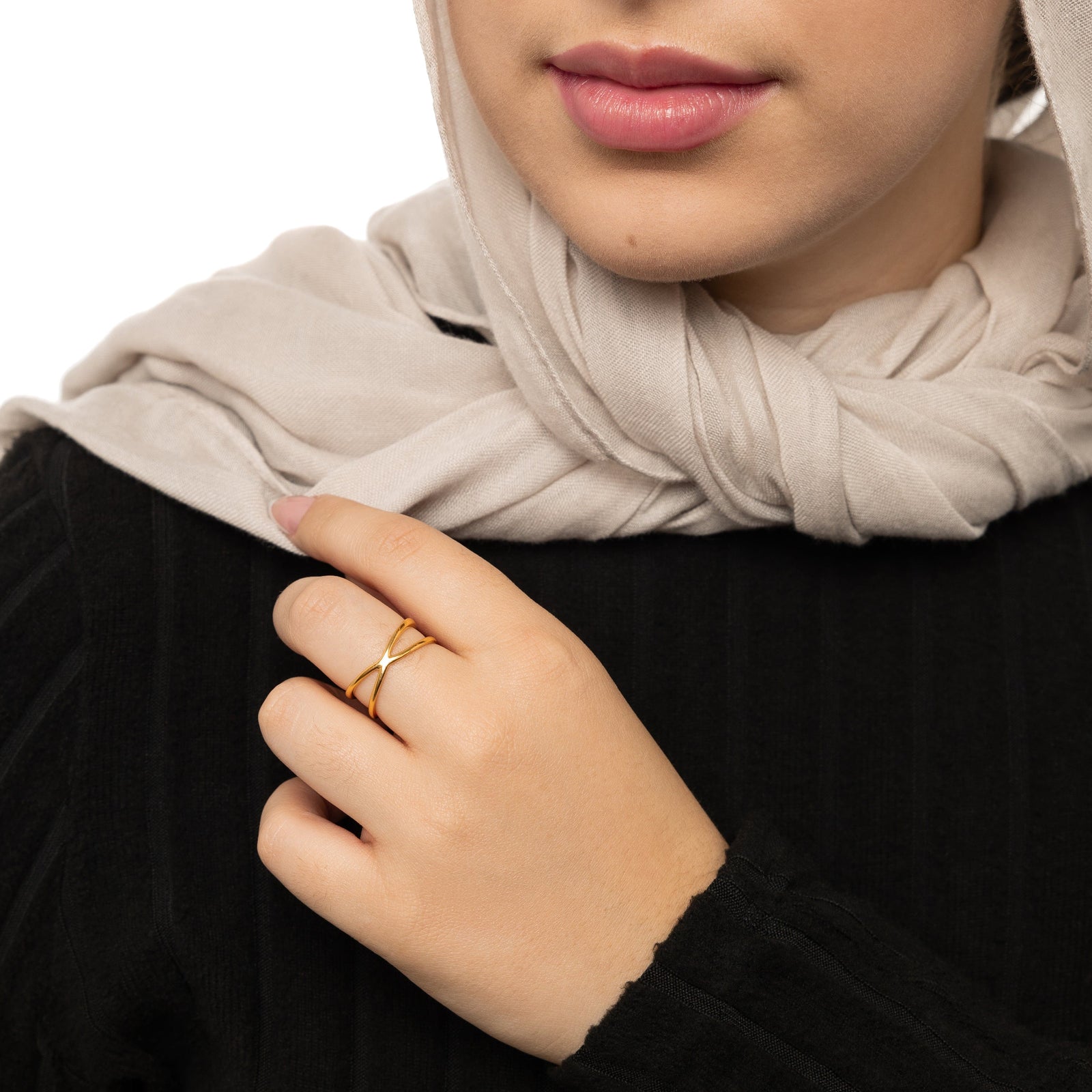 Close-up of a woman holding her hijab, a gold essential intersection ring paired with a black ribbed top.”