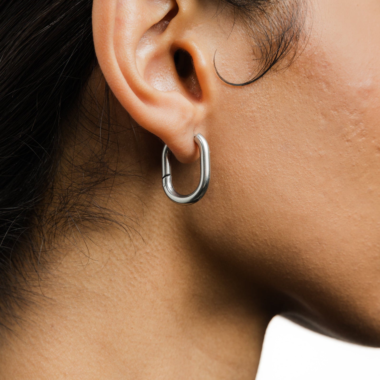 Close up of the silver Essential Oval Hoops as worn by the model on their right ear.