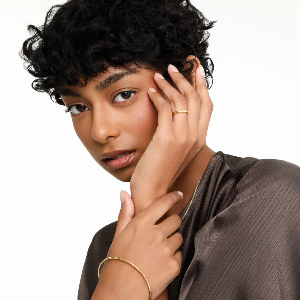 Photo of the gold Essential Ring as worn but he model on their left ring finger.
