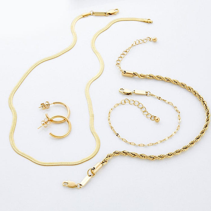Flat lay of gold jewelry including one necklace, one bracelet, one anklet, and a pair of hoop earrings on a white background.