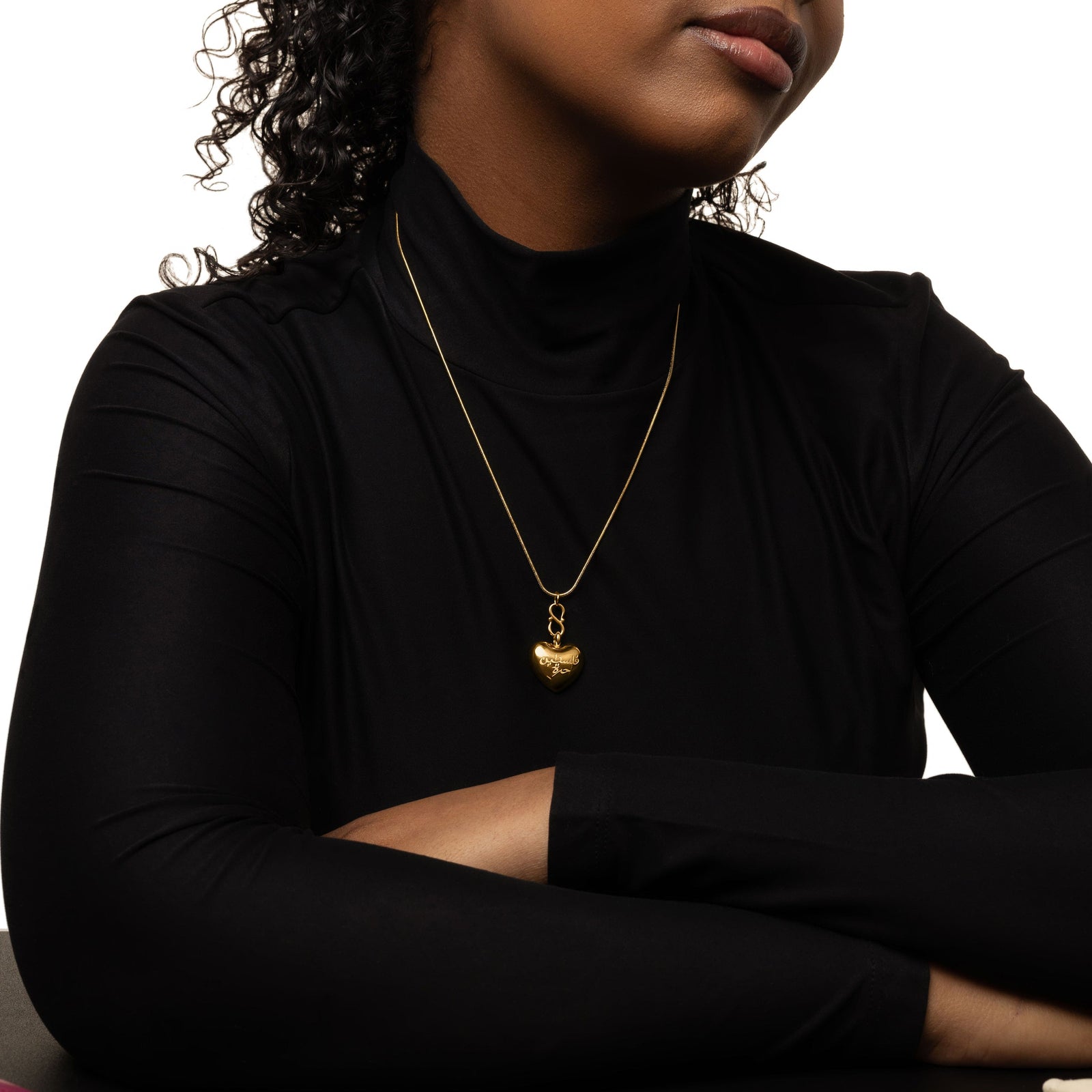 Photo of the model wearing a black longsleeves top. The model is also wearing the gold "Free Palestine" Heart Necklace.