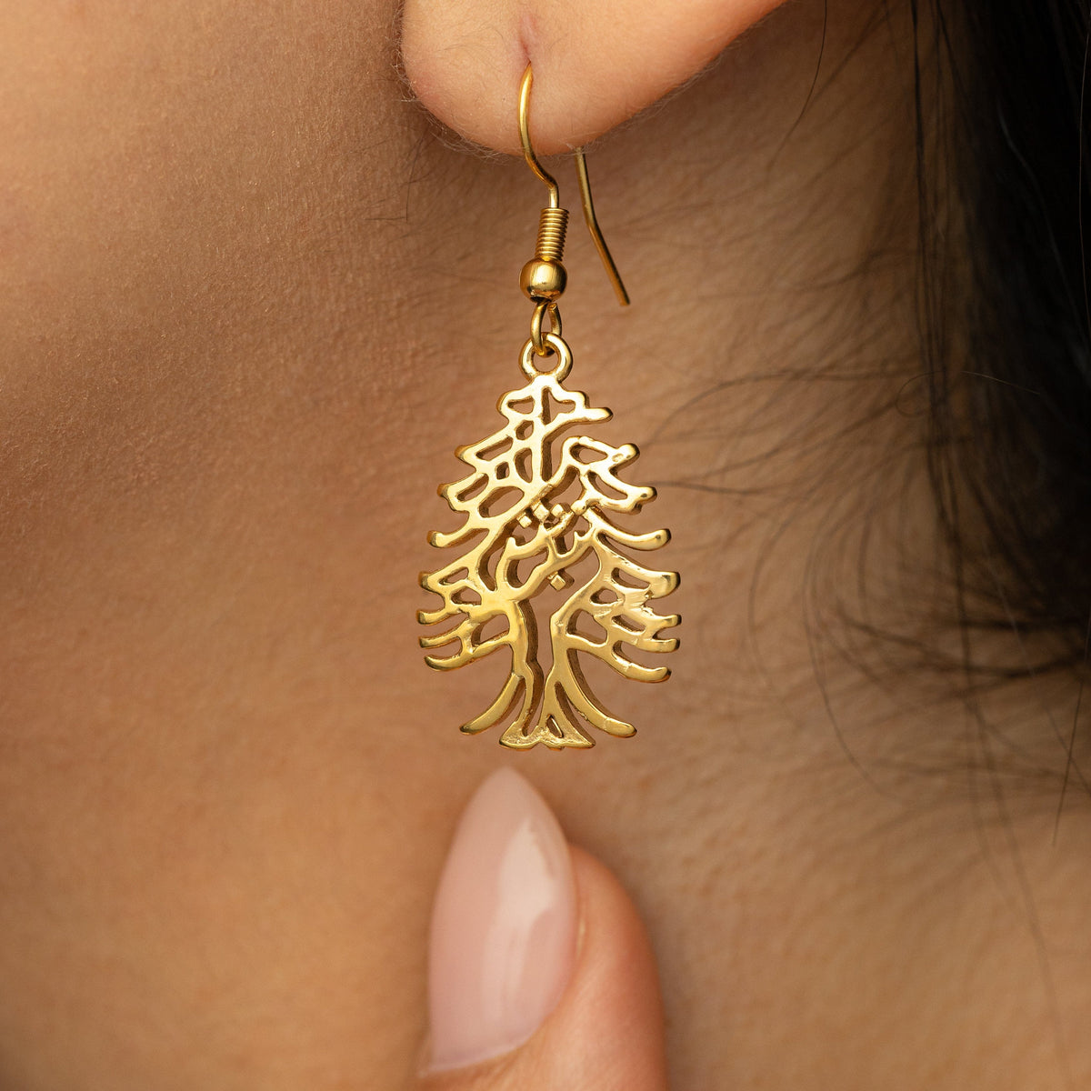 Close up photo of the dangling gold earring showing its intricate design.